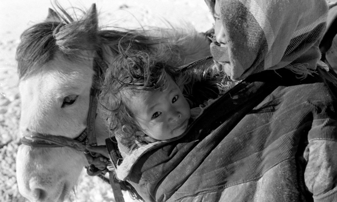 1990年3月，西藏當(dāng)雄縣納木湖鄉(xiāng)三村女牧民斯卓不畏嚴(yán)寒，懷抱幼子，準(zhǔn)備到遠(yuǎn)處放牧。新華社記者覺果攝